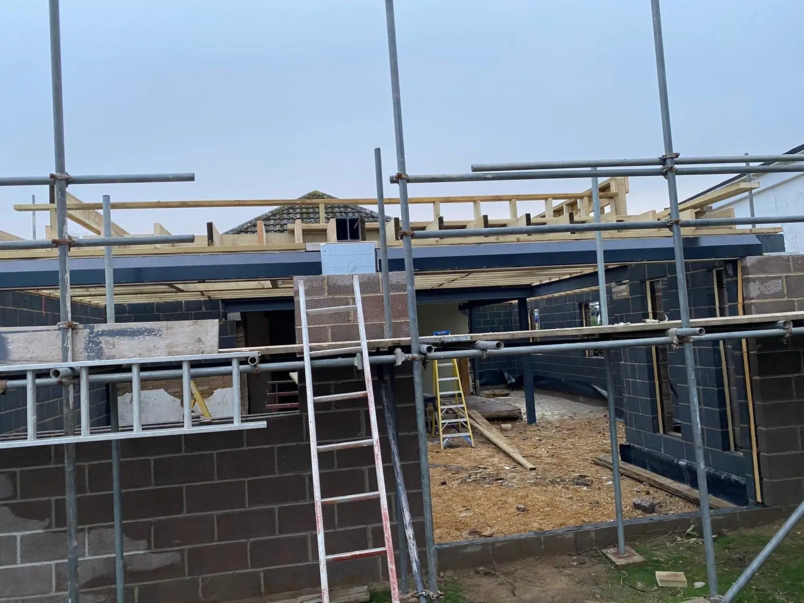 New roof timbers and steels seen from the scaffold, with the walls up to plate height