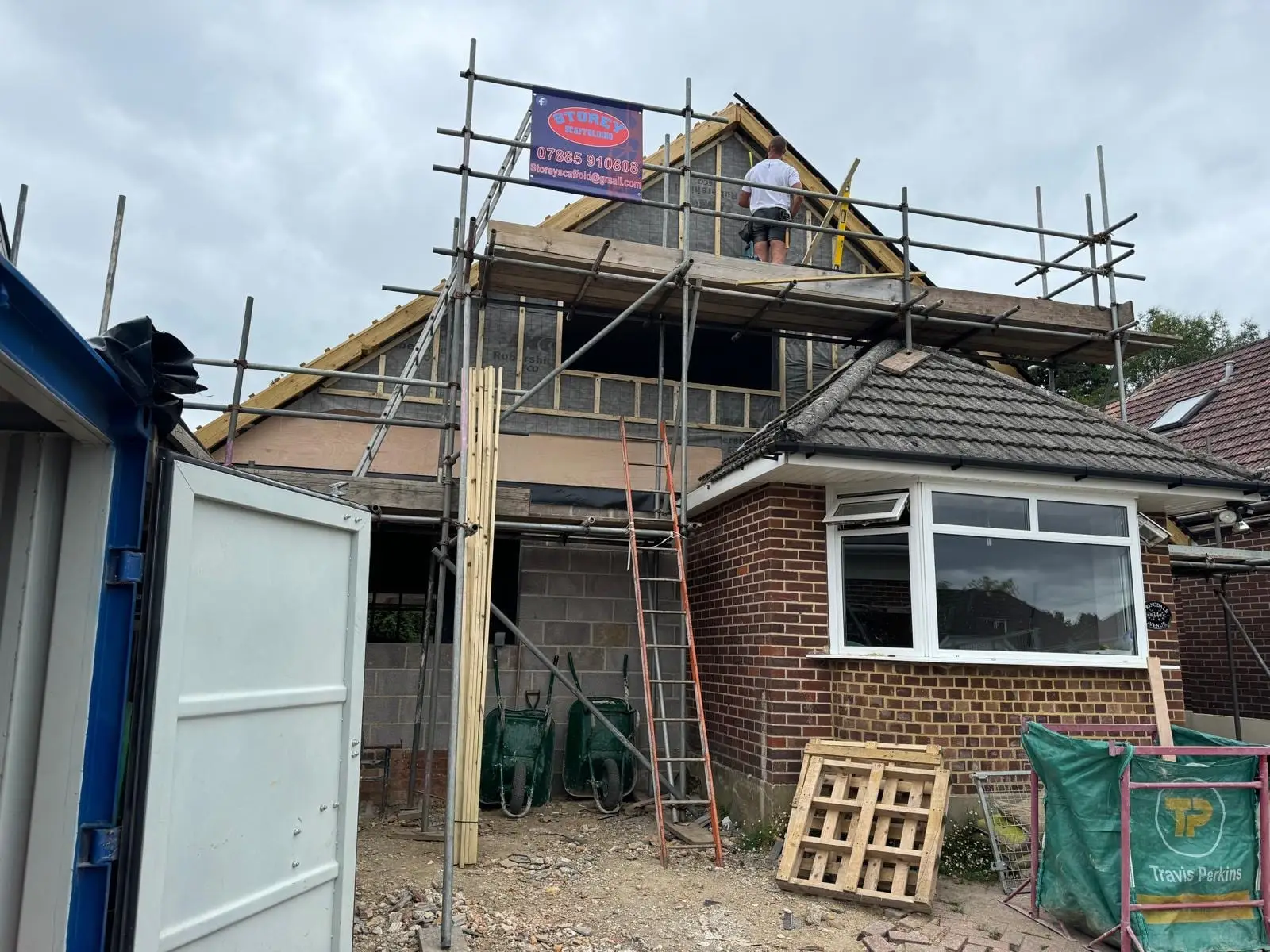 The roof off and the new first floor going up behind the scaffold, with the original bay still in place