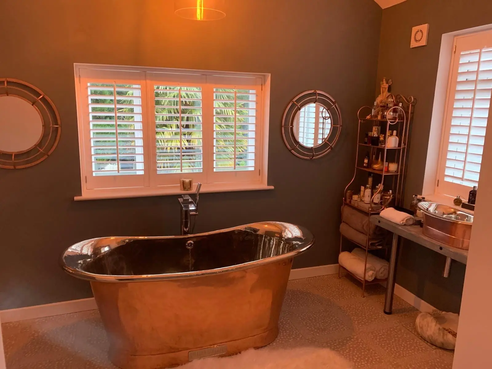 A copper roll top bath under plantation shutters in one of the finished bathrooms