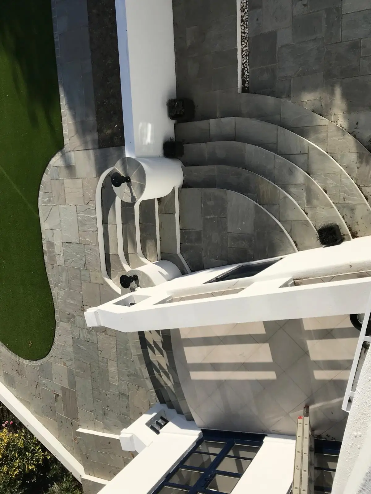 Curved stone steps and rendered walls in the new landscaping, seen from above