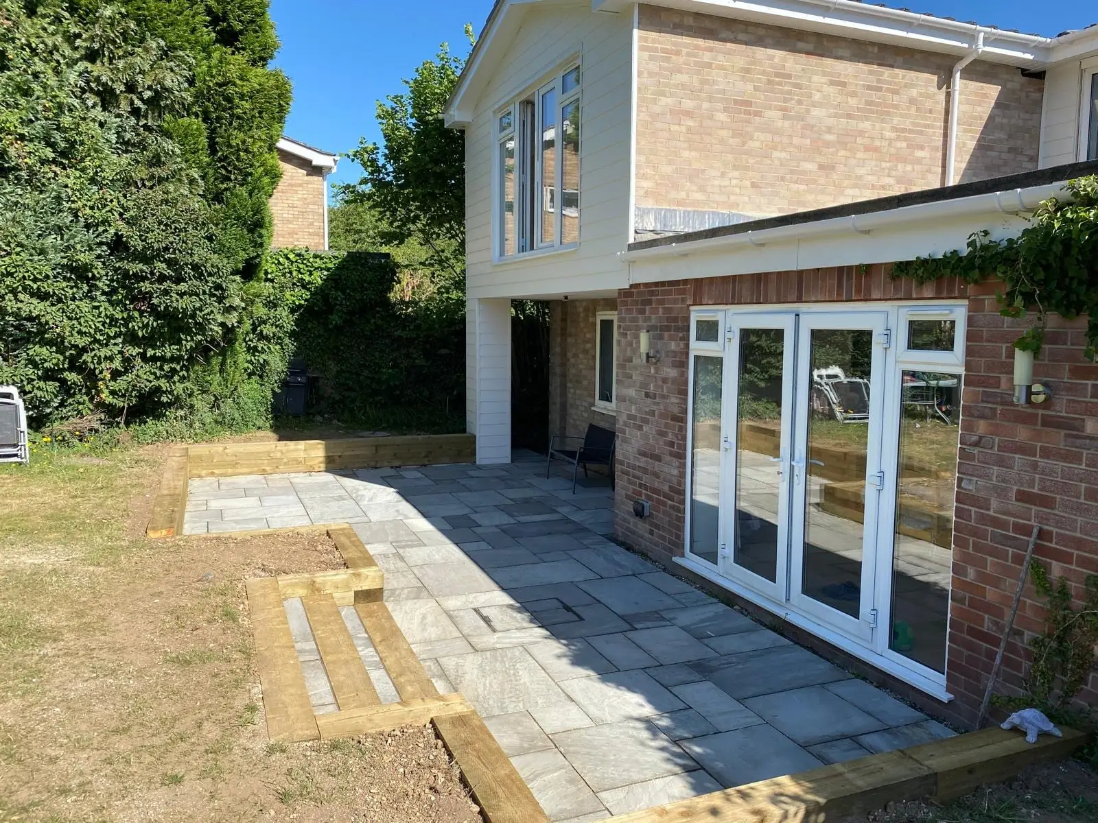 The new sandstone patio with sleeper steps up to the lawn