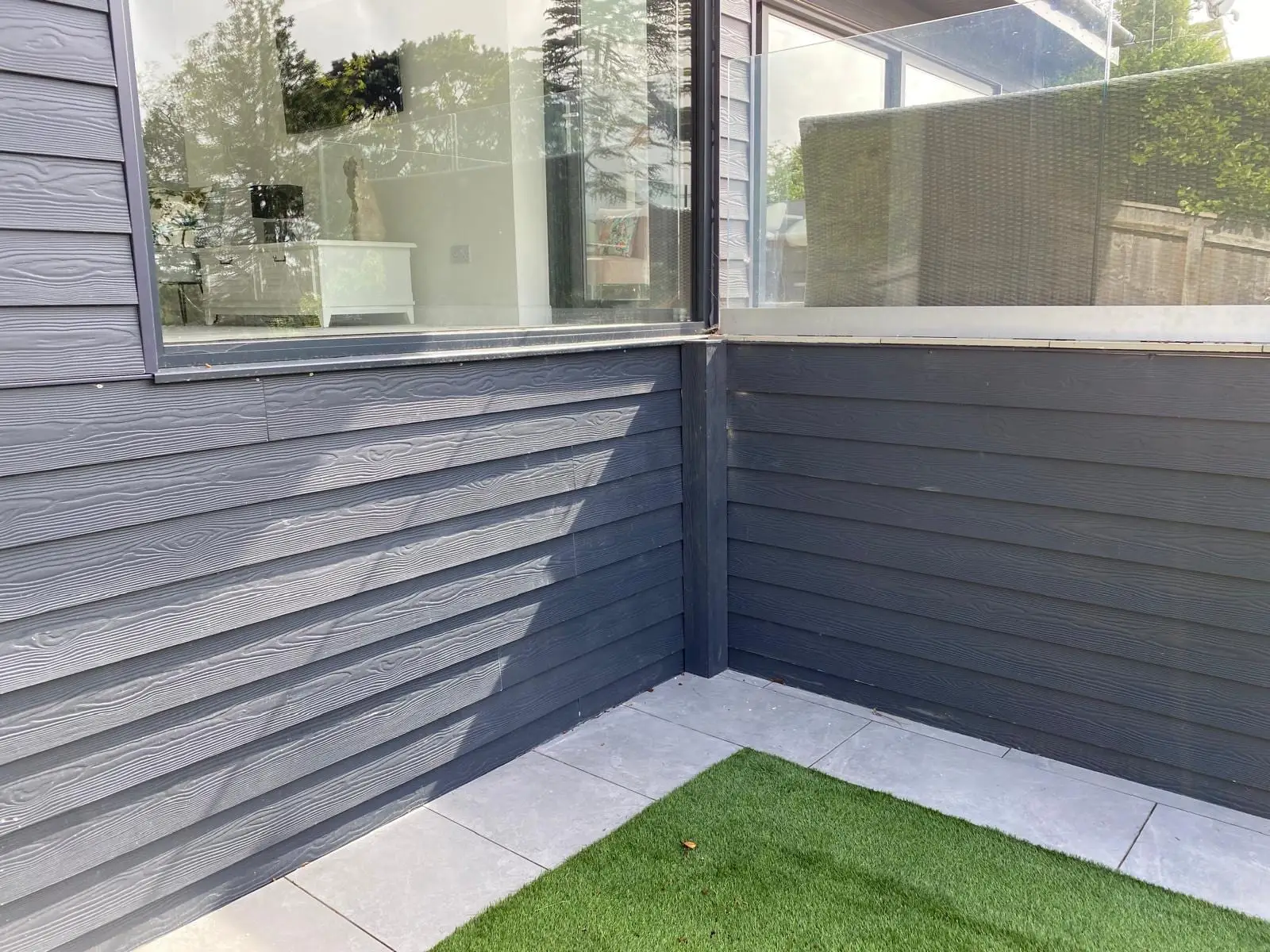 Close up of the grey composite cladding meeting the porcelain edging and lawn