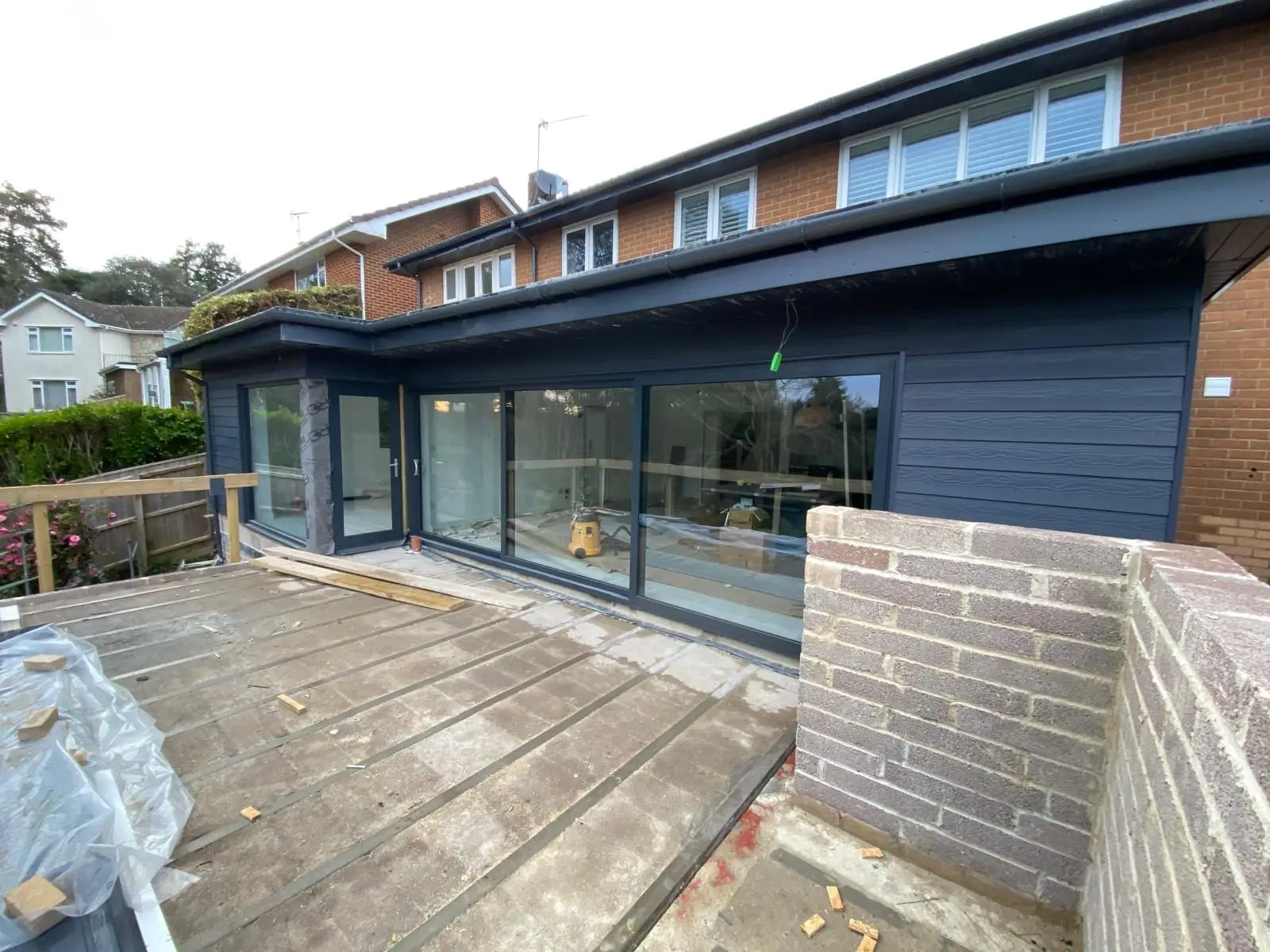 The same elevation clad in dark grey composite boarding with the fascia and garage door finished