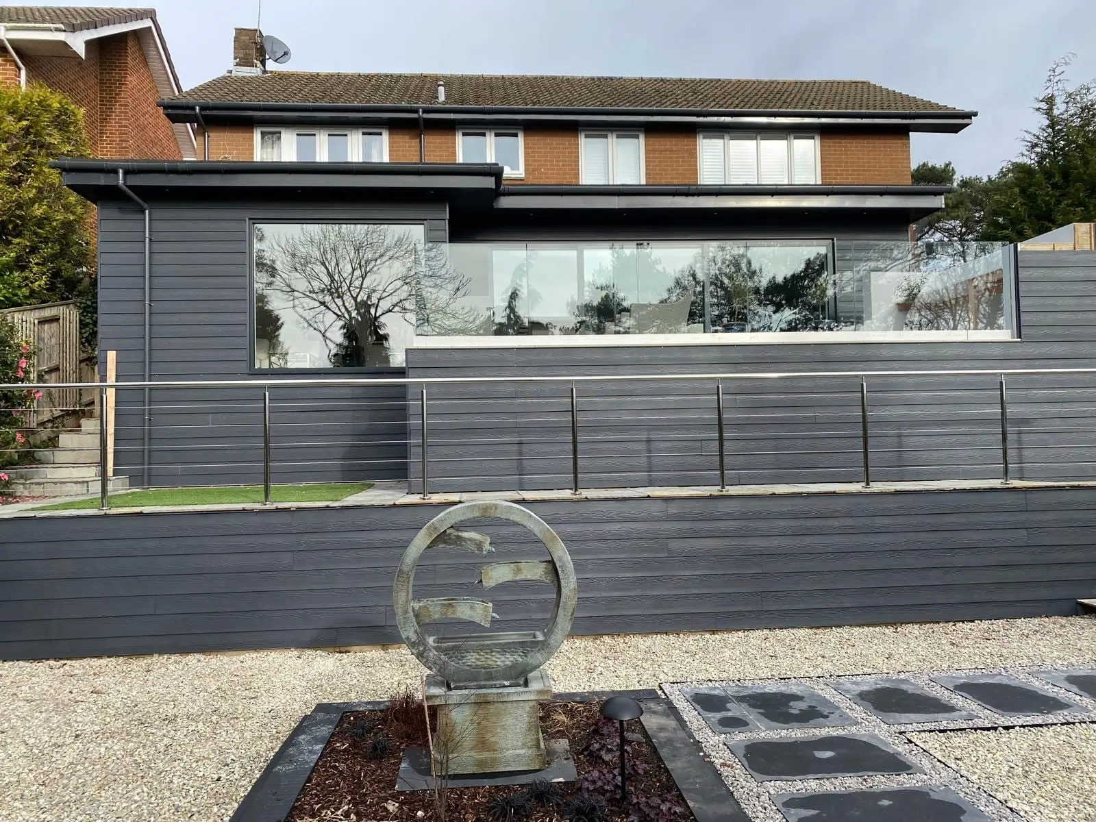 A finished contemporary rear extension and raised terrace seen from the garden