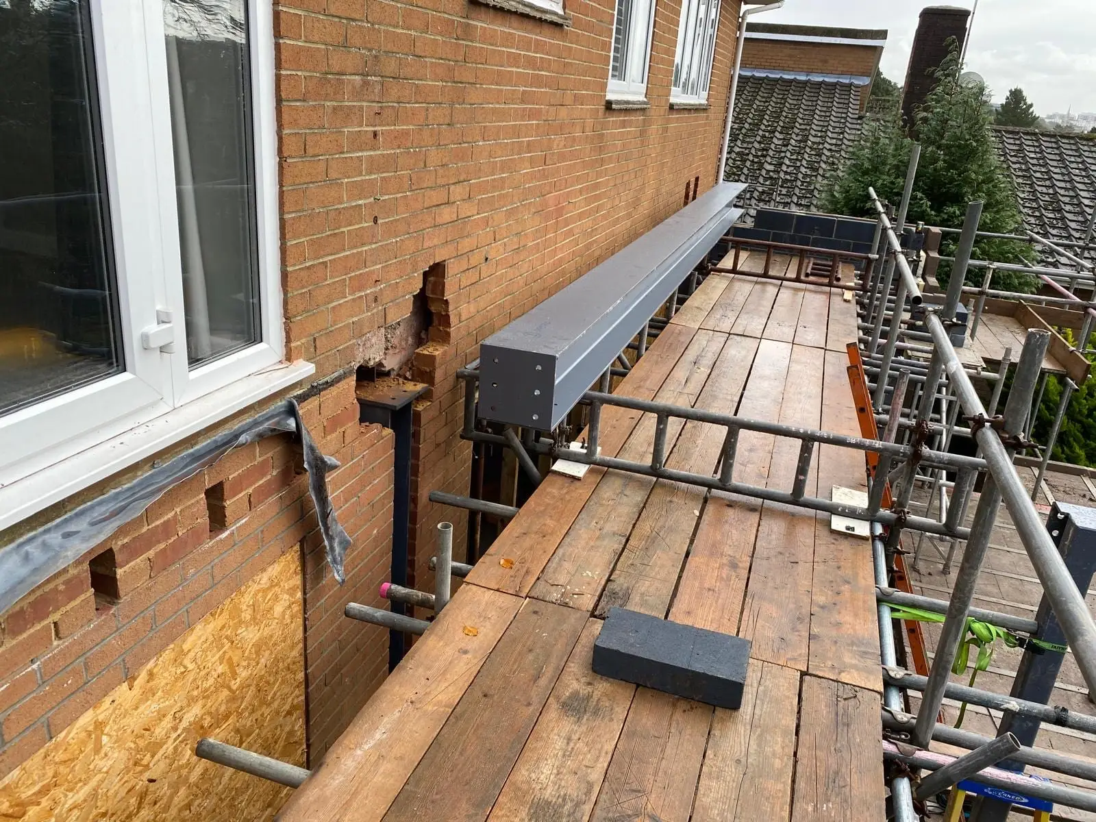 A steel beam bedded into pockets cut in the original brickwork, seen along the scaffold