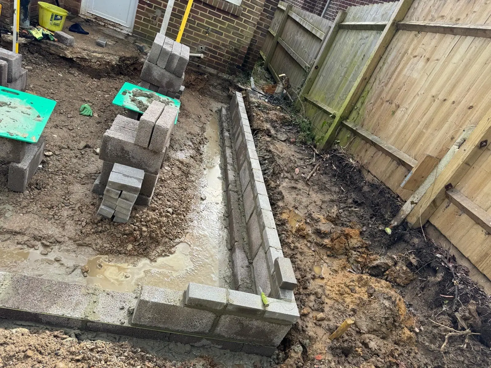 Foundations poured and the first course of blockwork laid along a new wall